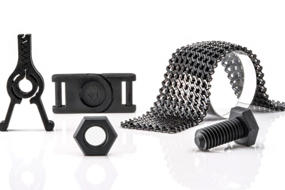 Verschiedene 3D-gedruckte Bauteile und Gegenstände wie zum Beispiel Schnappverbindungen und Schrauben auf weißem Hintergrund. Die Teile bestehen aus Evolution HI, einem schwarzen Kunststoff.