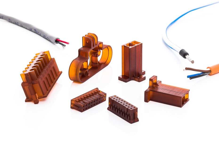 A variety of 3D printed parts made from the material ThermoBlast, placed on a white background. They are different components used in electronics such as connectors.